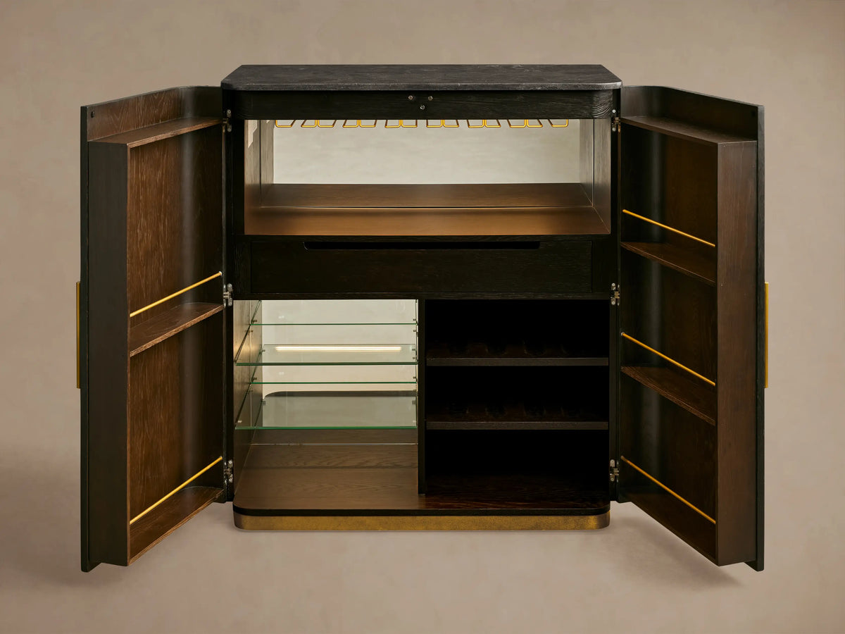 Brass-finished glass rack inside Finnley Plinth Bar Cabinet with hanging wine glasses, illuminated by an LED light.