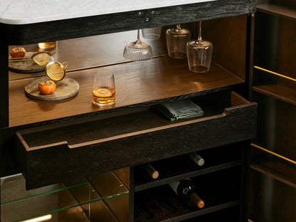 Open Ebony Finnley Plinth Bar Cabinet with white marble top, brass hardware, wine storage, glasses, & bar tools inside.