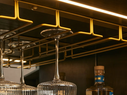 Close-up of dark ebony Finnley Bar Cabinet, open drawer, wine storage, mirrored shelf with drink, persimmons, & glasses.