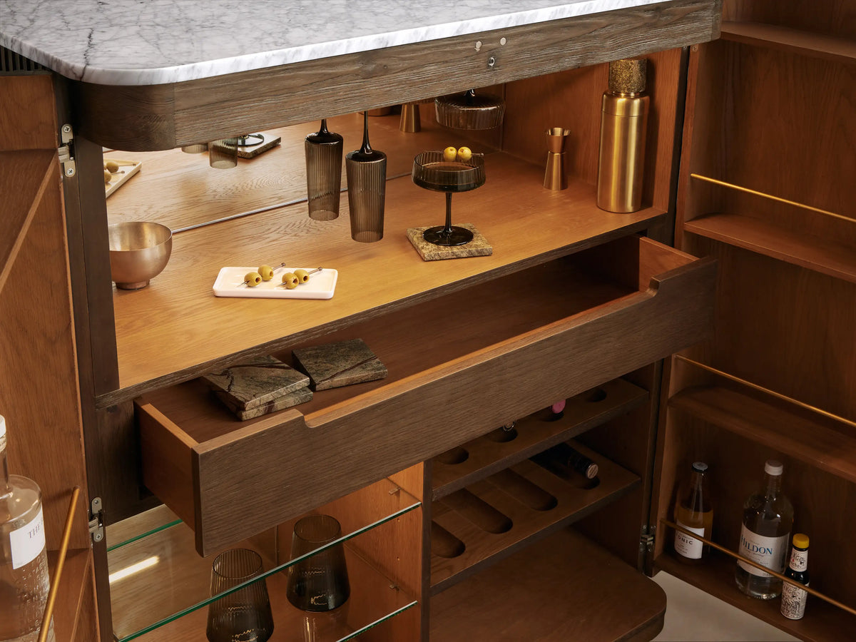 Finnley Plinth Bar Cabinet, open, showing mocha exterior, honey oak interior, white marble top, brass hardware, wine racks, glass storage.