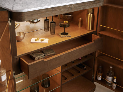 Finnley Plinth Bar Cabinet, open, showing mocha exterior, honey oak interior, white marble top, brass hardware, wine racks, glass storage.