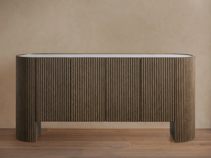 Flore Sideboard with reeded oak wood detailing, laminate frame, and a Carrara marble top, standing on a wooden floor against a beige wall.