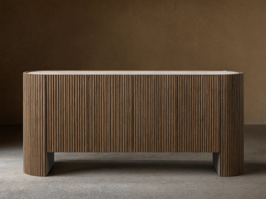 Flore Sideboard with reeded oak wood detailing, laminate frame, and a Carrara marble top, standing on a wooden floor against a beige wall.