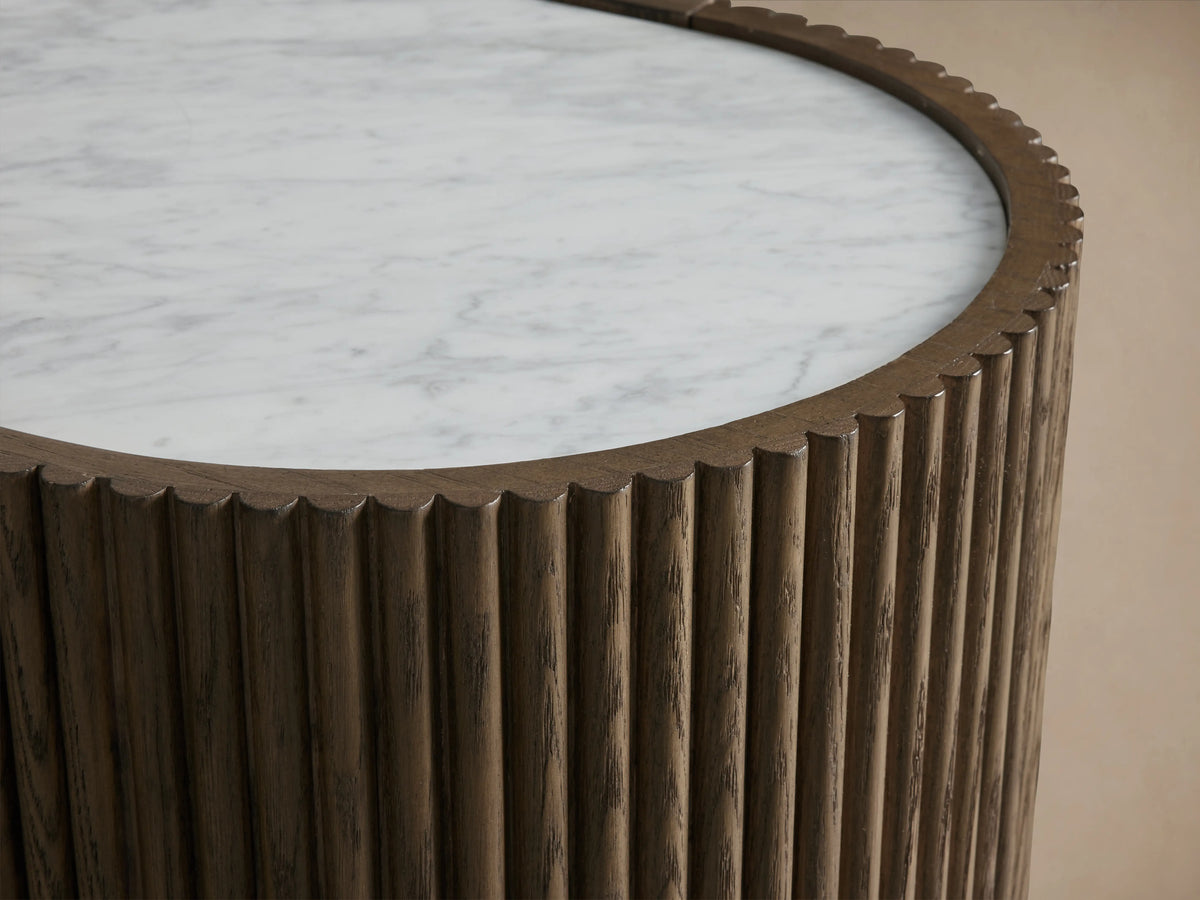 Flore Sideboard with reeded oak wood detailing, laminate frame, and a Carrara marble top, standing on a wooden floor against a beige wall.