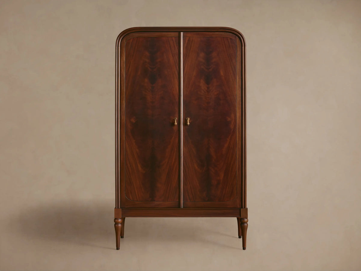 Frances Cabinet: Dark mahogany with unique figured grain. Rounded top, one door open showing shelves and decorative items. Brass knob.