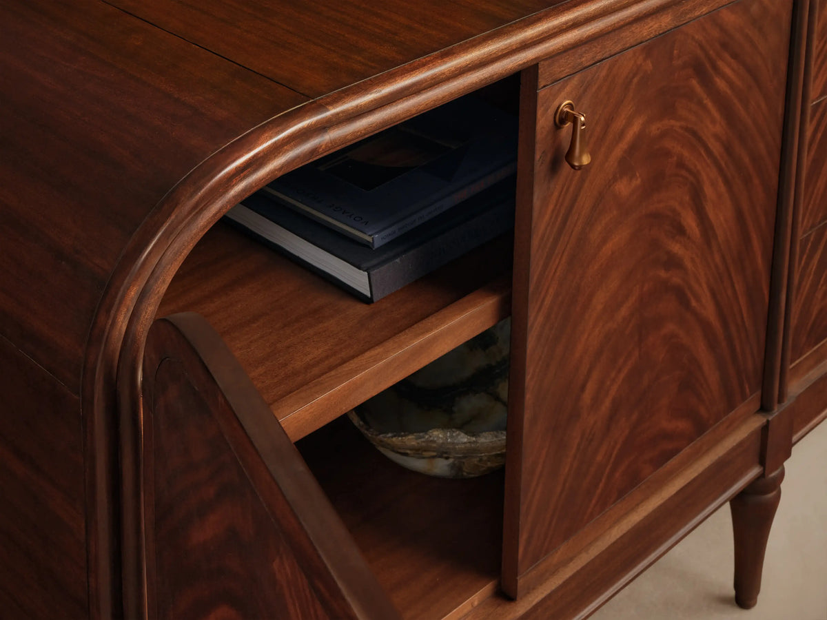 Close-up, angled view of a dark reddish-brown Frances Sideboard with Drawers, showing an open compartment, rounded top edge, wavy wood grain, and a brass handle.