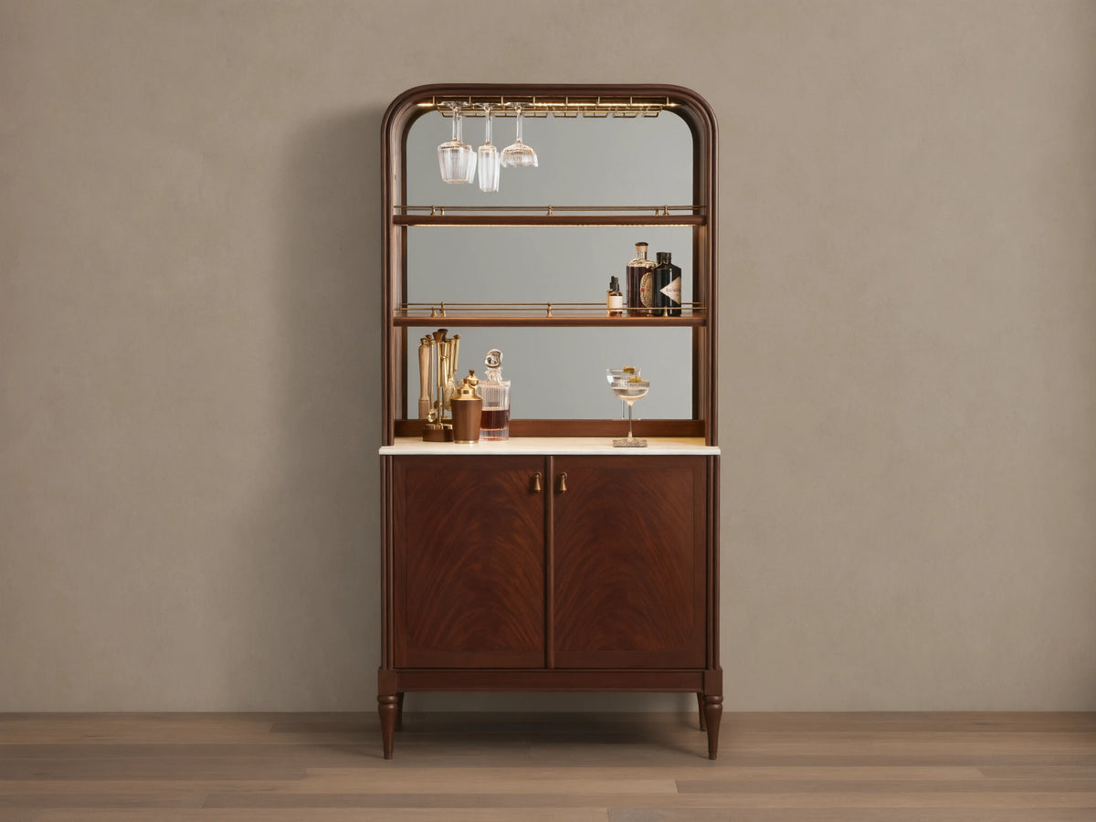 Front view of the Frances Bar Cabinet in dark mahogany with flame grain, brass stemware rack, marble top, and spirits.