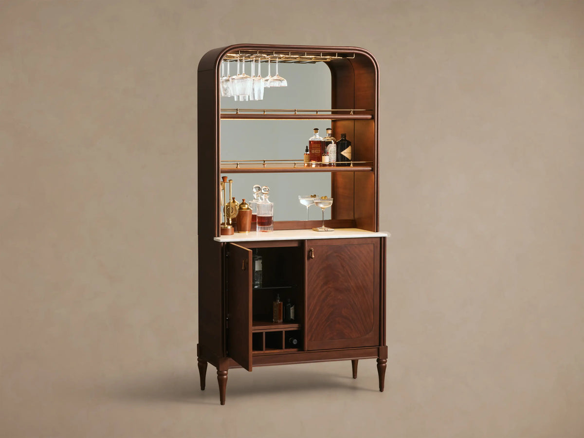 Front view of the dark mahogany Frances Bar Cabinet with a rounded top, brass stemware rack, marble workspace, and one open lower door.