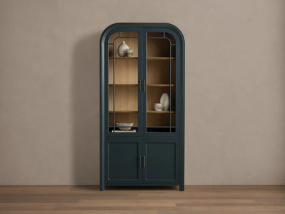 Front view of the Dark Blue Gatlin Glass Cabinet with an arched top, glass doors, wood shelves, and brass pulls.