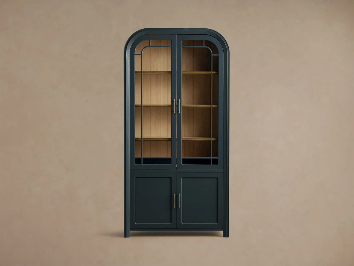 Front view of the Dark Blue Gatlin Glass Cabinet with an arched top, glass doors, wood shelves, and brass pulls.