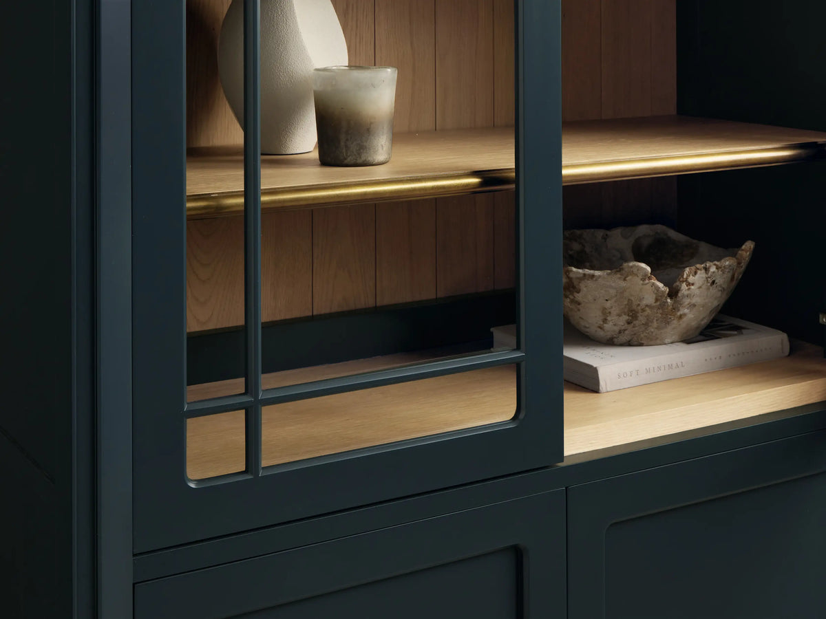 Front view of the deep teal Gatlin Glass Cabinet, featuring an arched top, two glass doors revealing wooden shelves, and two solid doors with brass pulls.