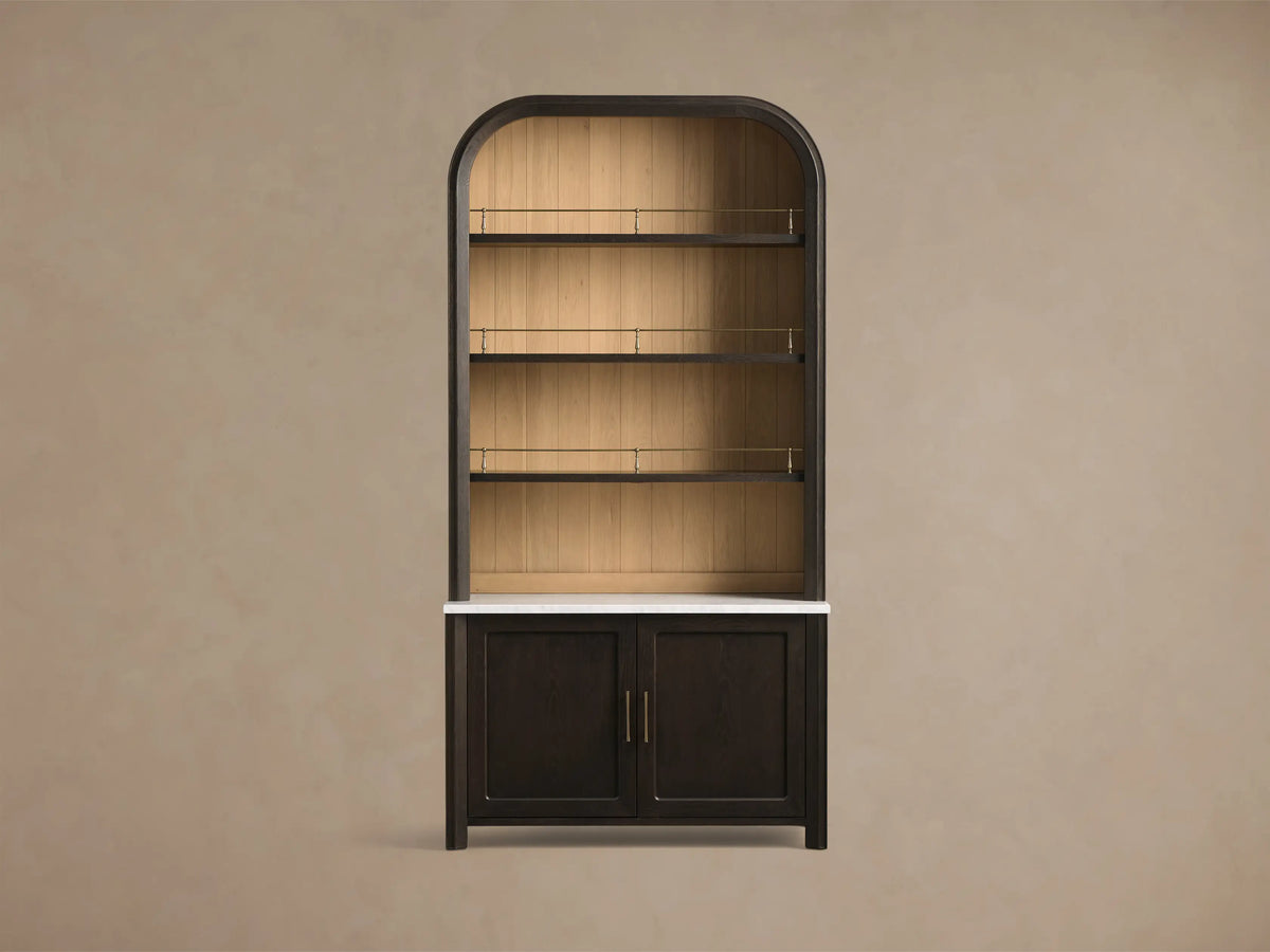 Front view of a mocha-toned Gatlin Hutch with an arched top, three shelves with antique brass rails, white marble top, and lower cabinet doors.