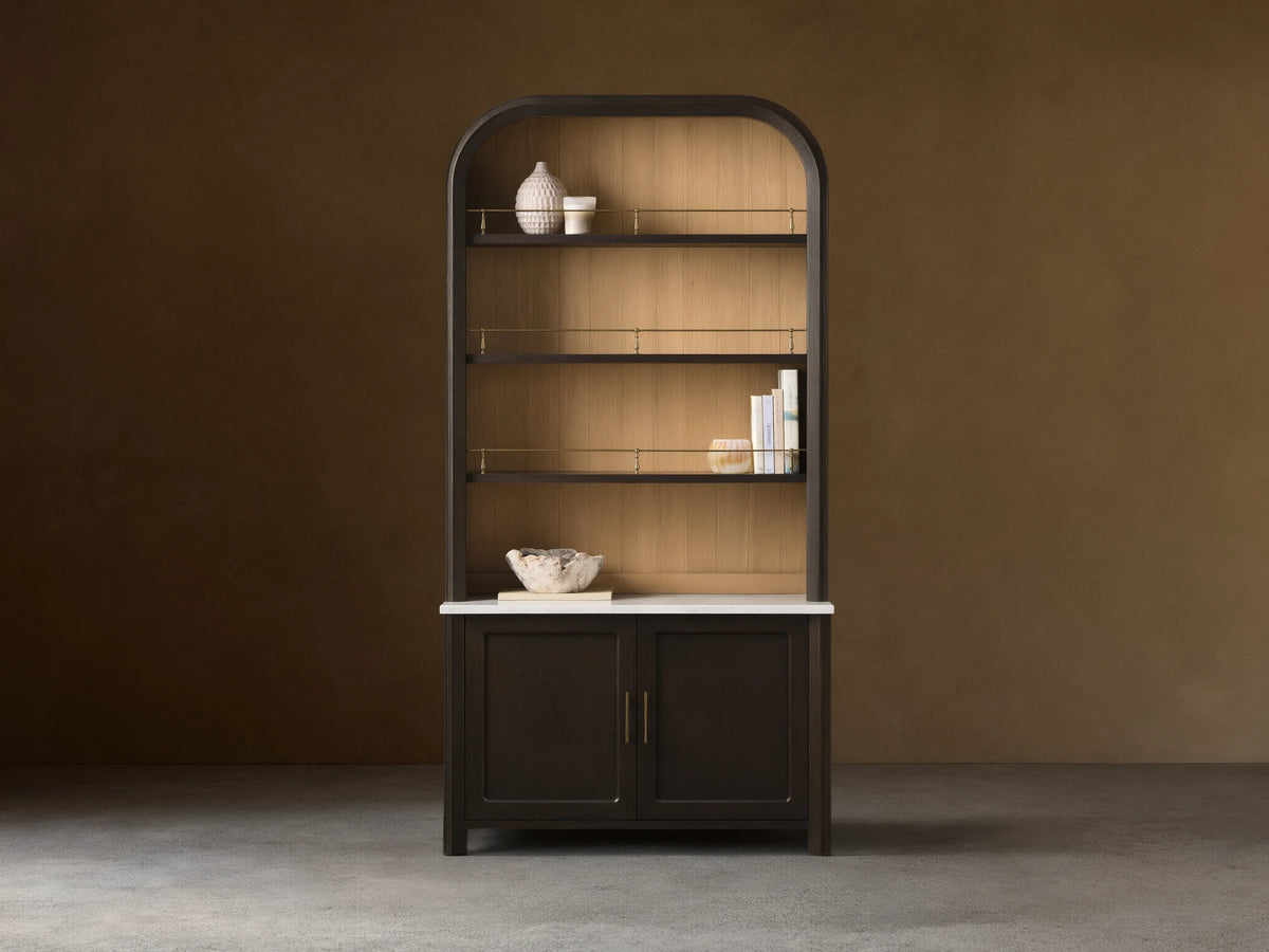 Front view of the Gatlin Hutch, a dark mocha wood hutch with an arched top, natural wood back panel, white marble, and brass accents.