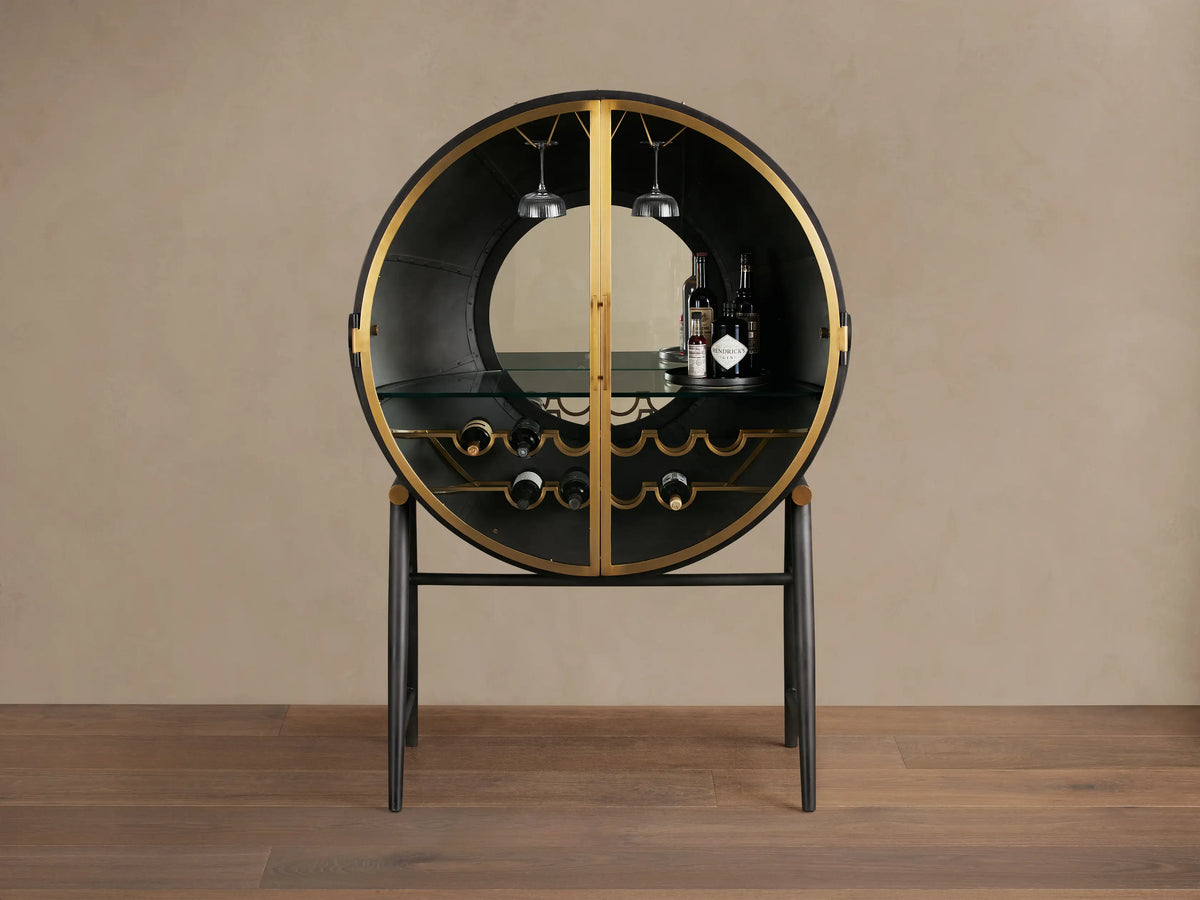 Circular Gideon Bar Cabinet with open doors, featuring dark wood interior, gold accents, built-in glass rack, and bottles inside.