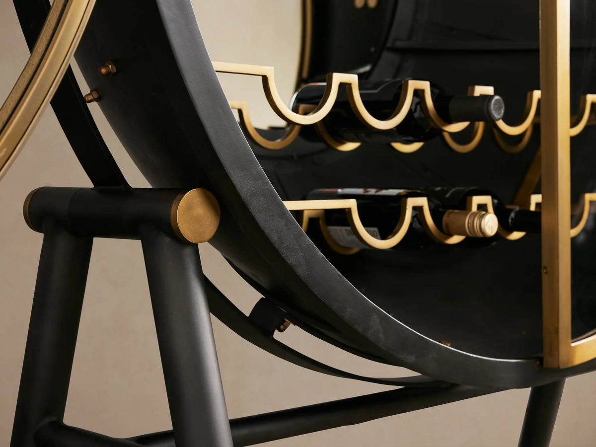 Gideon Bar Cabinet with round, metallic black structure, gold accents, and circular front on a black stand.
