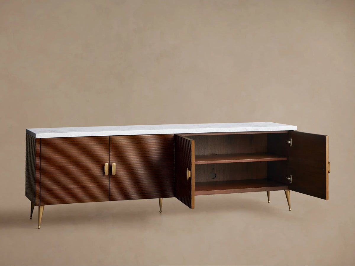 Giselle Media Console: Long dark mahogany console with reeded doors, white marble top, brass bar handles, and tapered legs.