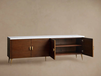Giselle Media Console: Long dark mahogany console with reeded doors, white marble top, brass bar handles, and tapered legs.
