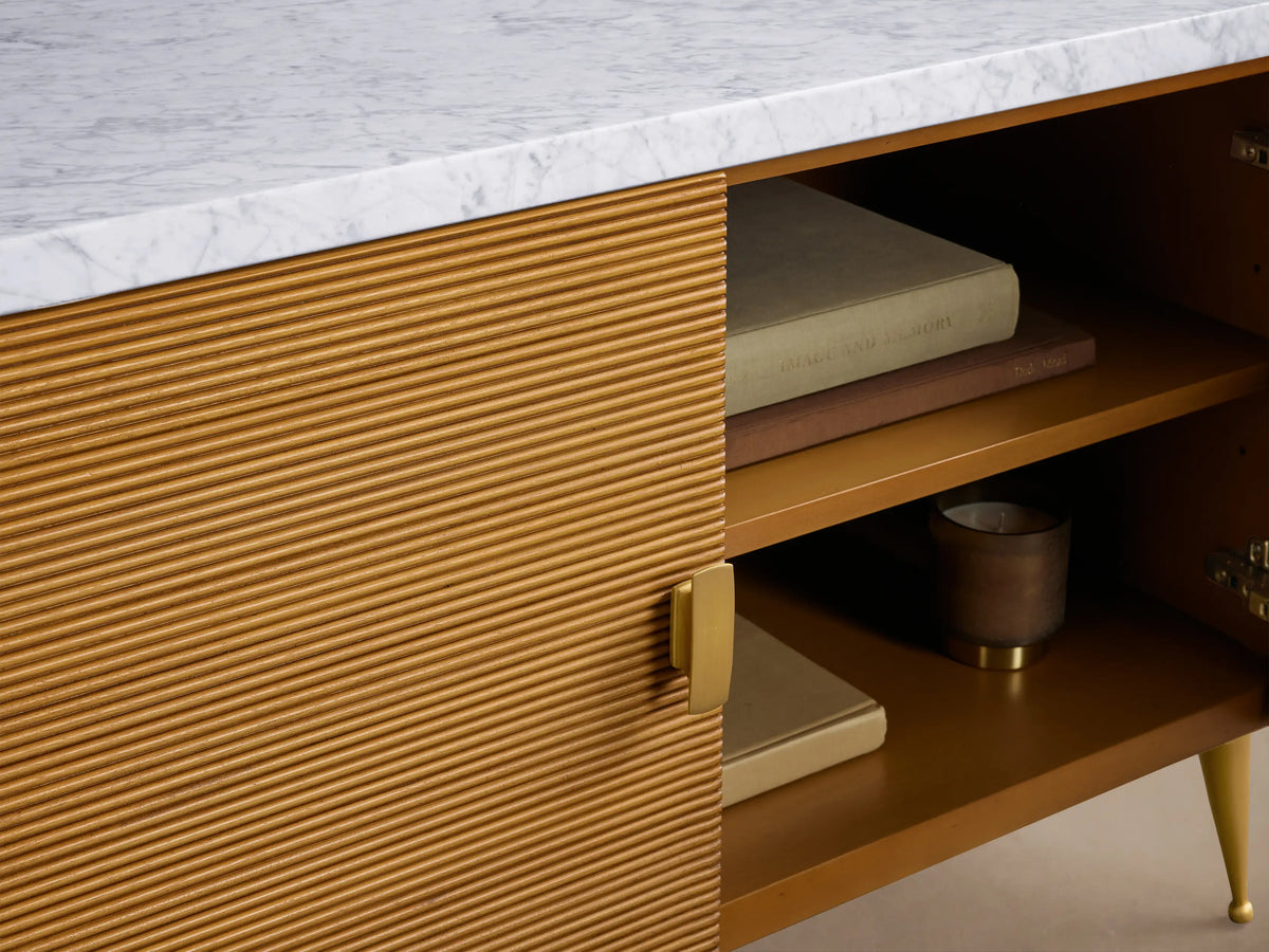 Giselle Media Console with white marble top, light brown reeded body, brass handles & tapered legs. One door open shows shelves.