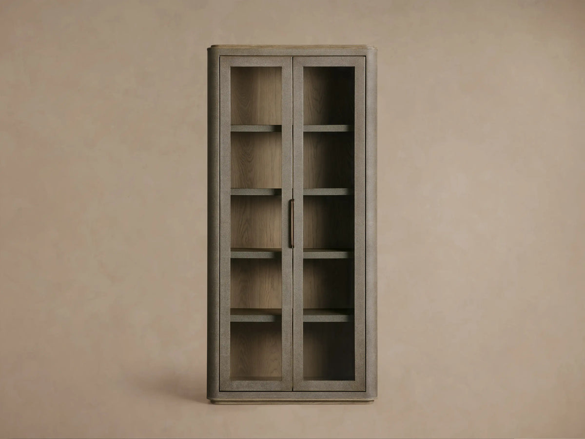 Front view of the light beige Cove Harrow Cabinet, a faux shagreen cabinet with two glass doors and champagne-brass handles.