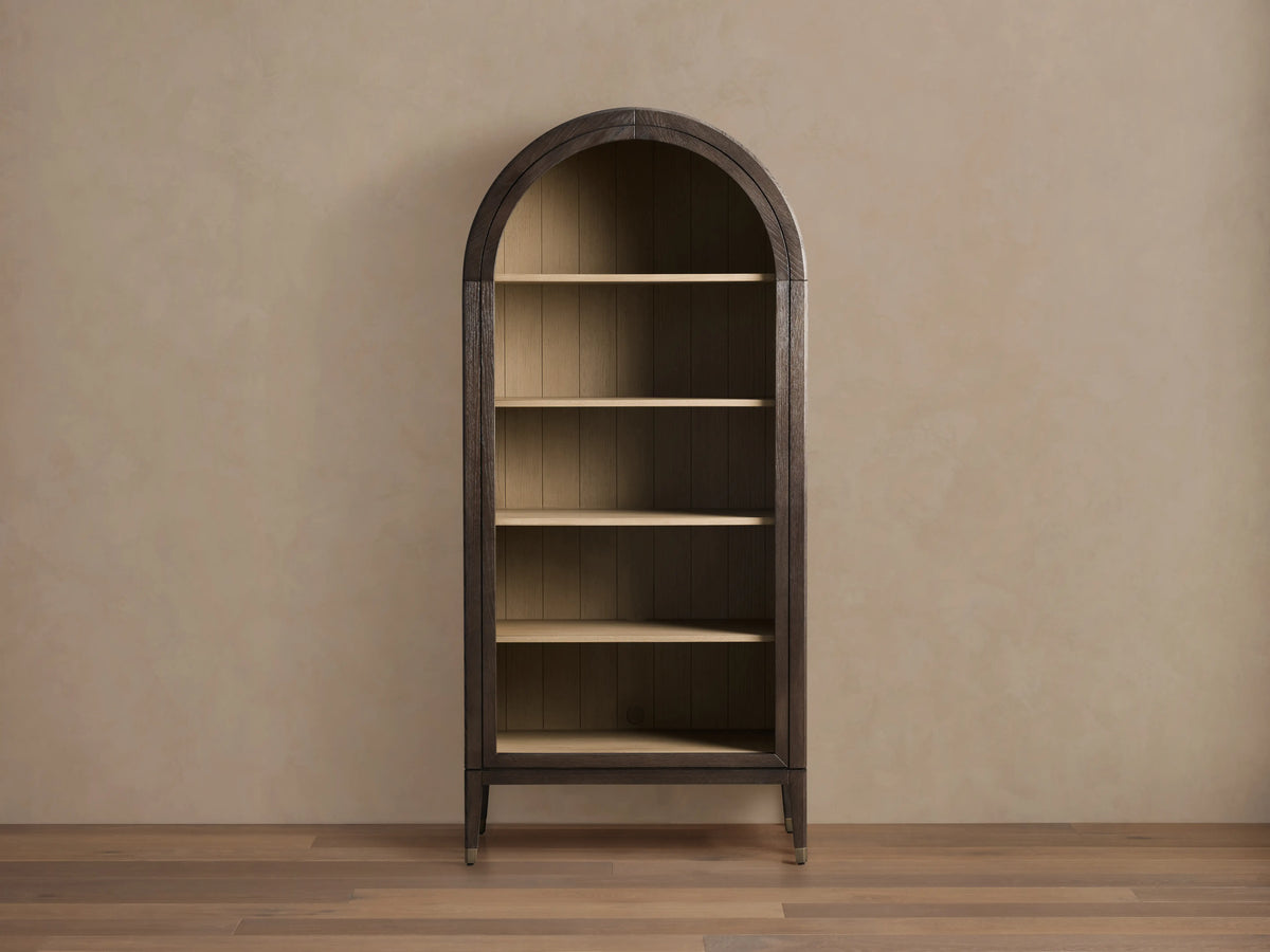 Arched Hattie Bookcase made of oak wood with shiplap back panel, adjustable shelves, and brass-capped feet on a wooden floor.