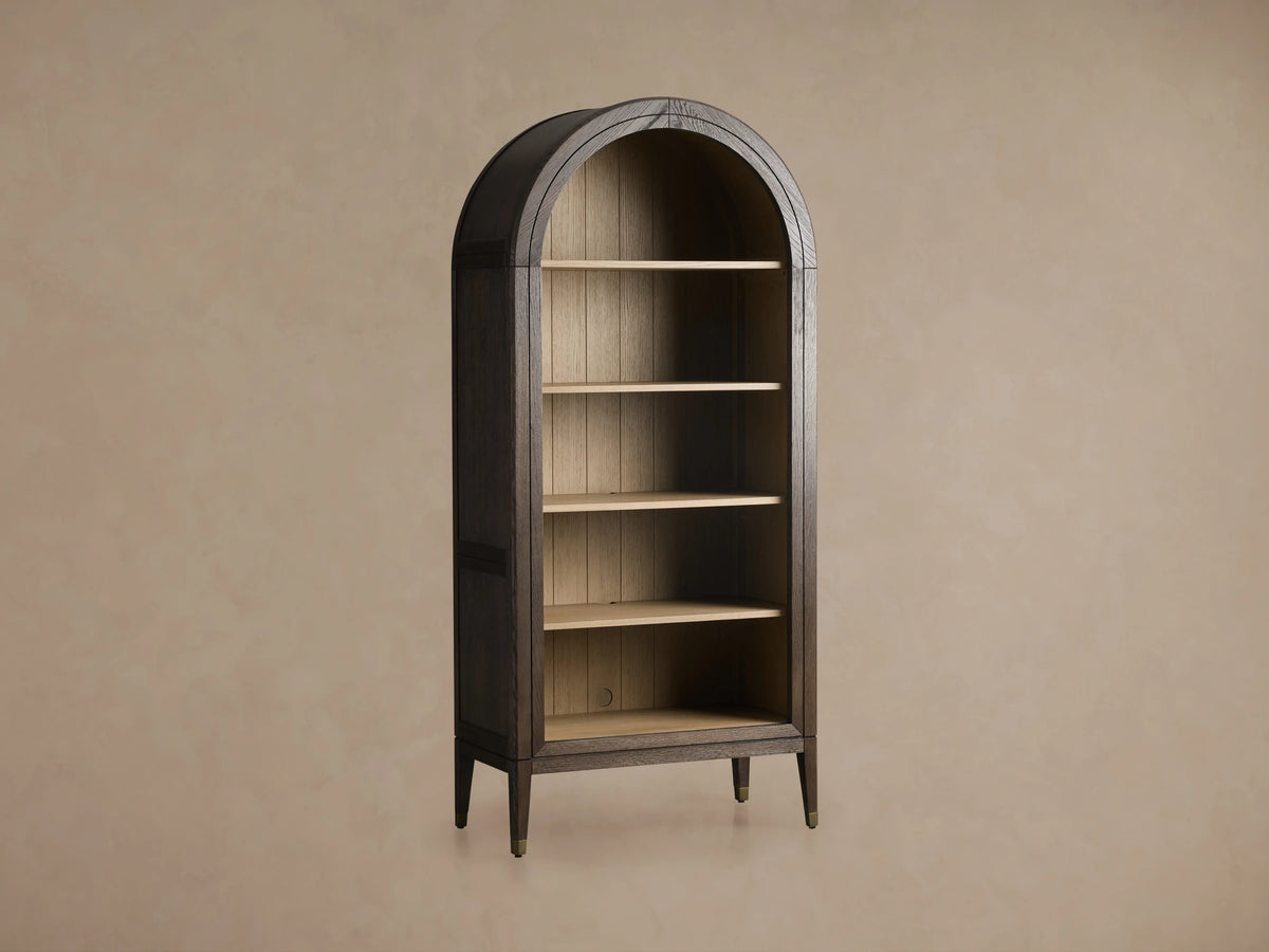 Arched Hattie Bookcase in dark oak with five shelves, shiplap back paneling, and brass-capped feet, set against a neutral background.