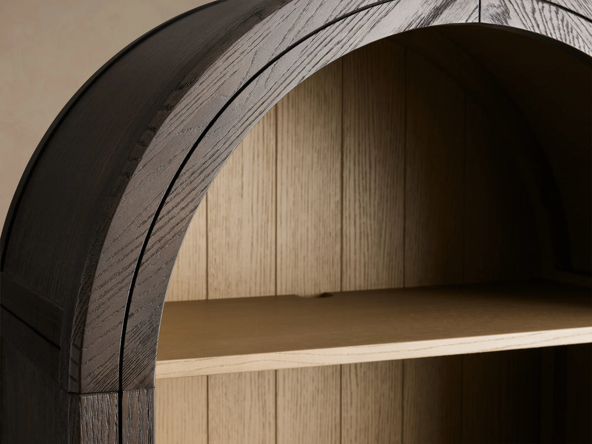Arched Hattie Bookcase made of oak wood with shiplap back panel, adjustable shelves, and brass-capped feet on a wooden floor.