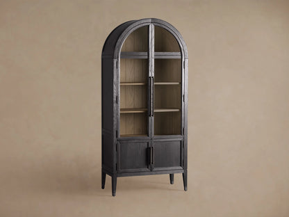 Front view of the Dark Hattie Glass Cabinet with an arched top, glass doors, light shiplap back panel, and reeded hardware.