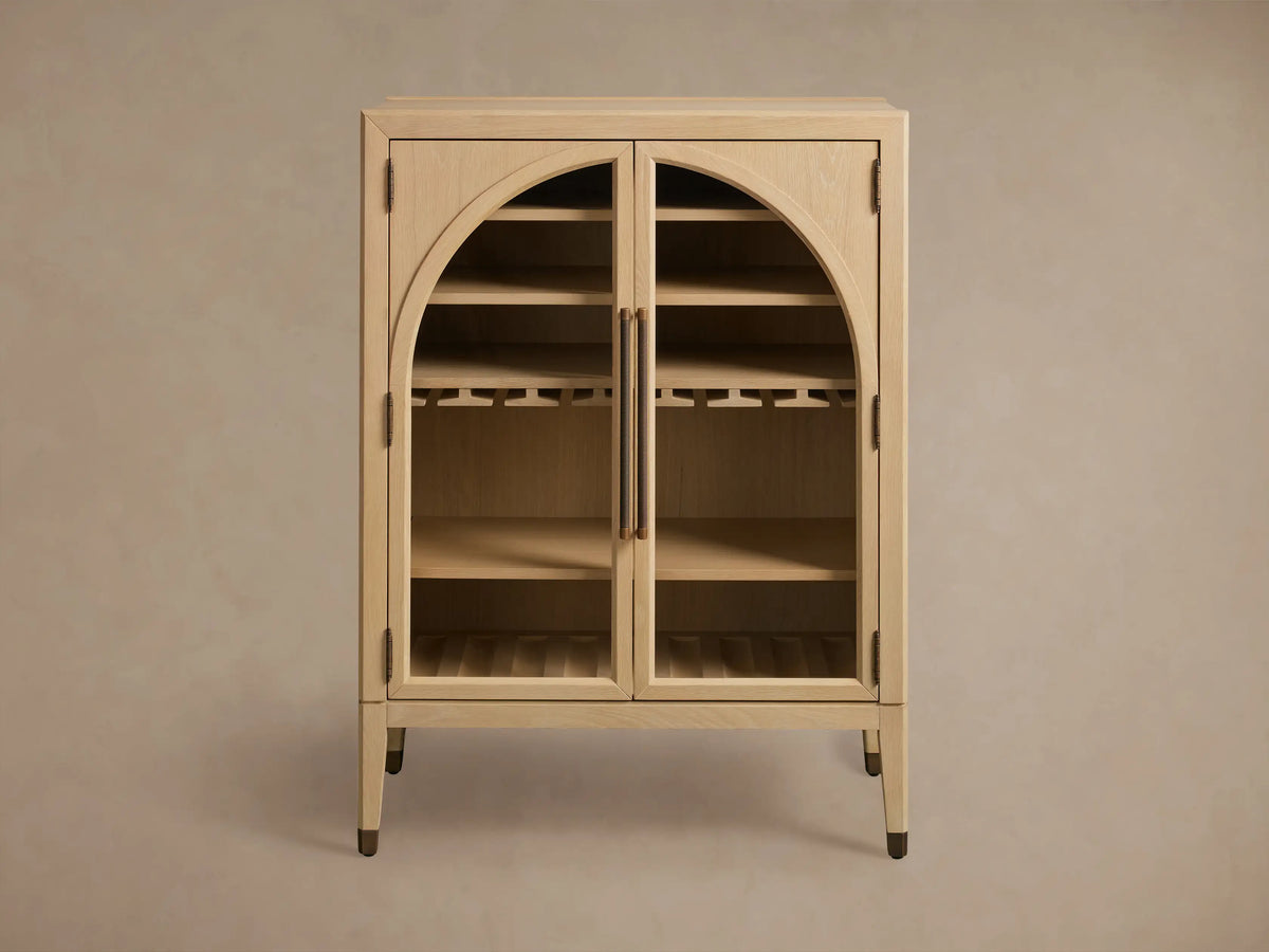 Alt text: Close-up of the Hattie Bar Cabinet's interior, showcasing solid oak shelves, brass-accented feet, and storage for stemware and bottles.