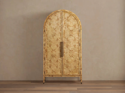 Hattie Burl Cabinet with arched top, swirling mappa burl pattern, brass-capped feet, and vertical reeded handles on closed doors.