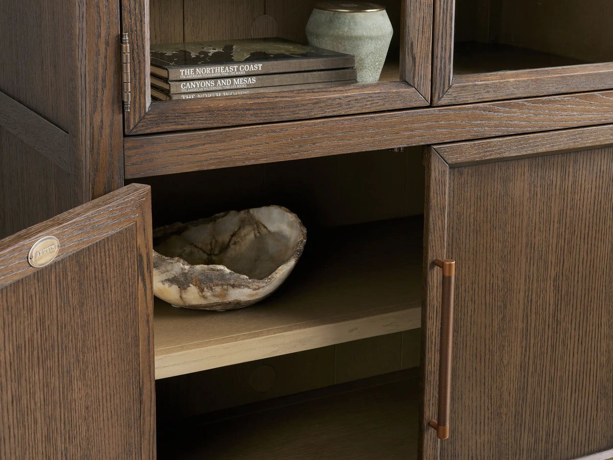 Hattie Squared Glass Cabinet in dark ebony wood, arched glass doors with lighter interior shelves, solid lower doors, bronze reeded handles.