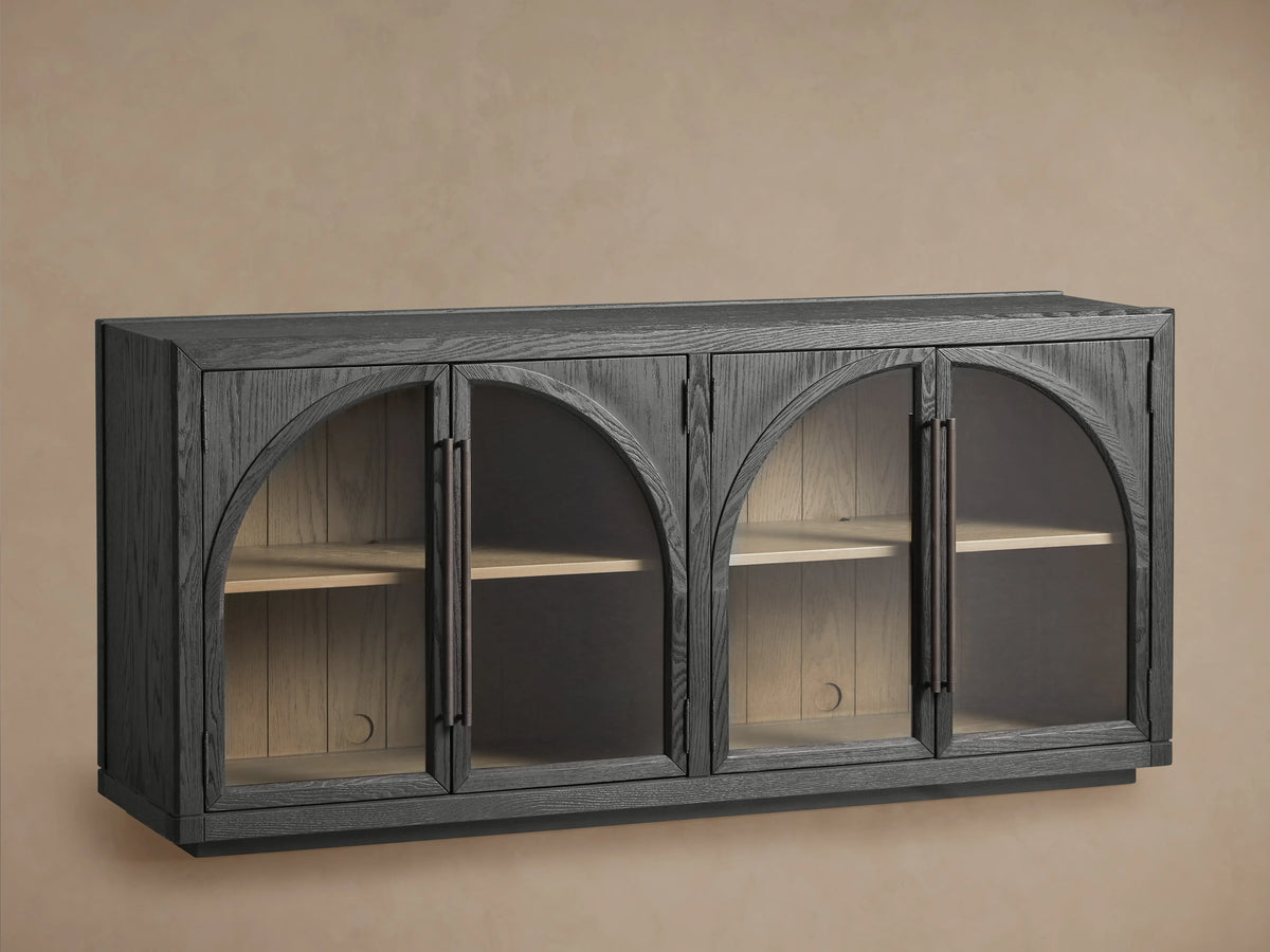 Hattie Sideboard made of dark oak with arched glass doors, showing interior shelves and shiplap back paneling against a neutral wall.