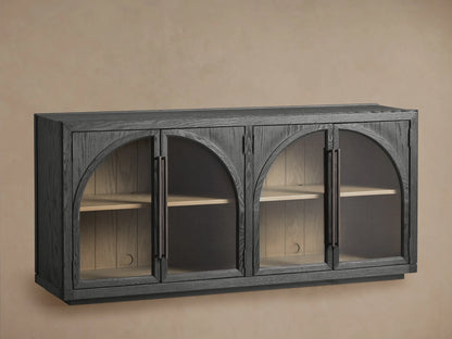 Hattie Sideboard made of dark oak with arched glass doors, showing interior shelves and shiplap back paneling against a neutral wall.