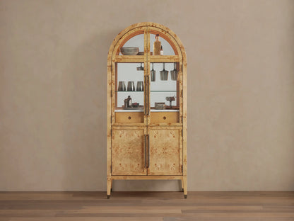 Hattie Burl Bar Cabinet, light mappa burl wood with arched top, glass doors revealing barware, and solid lower doors with brass hardware.