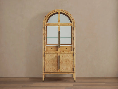 Hattie Burl Bar Cabinet, light mappa burl wood with arched top, glass doors revealing barware, and solid lower doors with brass hardware.