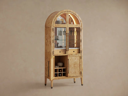 Hattie Burl Bar Cabinet's interior: light wood shelf, bottle, and dark stemware hanging from a metal rack, warmly lit.