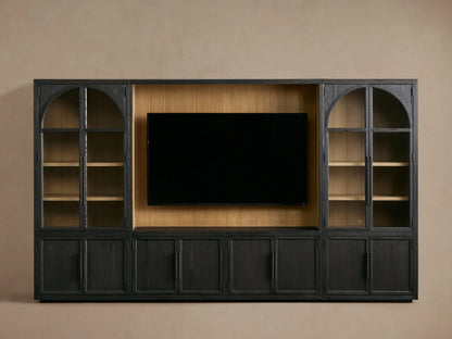 Front view of the dark Hattie Wall Unit, featuring a large TV in the center, flanked by glass-doored cabinets with arched tops and lighter shiplap back panels.
