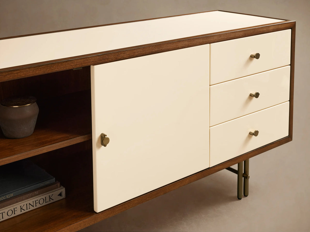 Henton Media Console with a cream finish, six drawers, and two doors. Brown wooden frame and metal legs, set against a neutral background.
