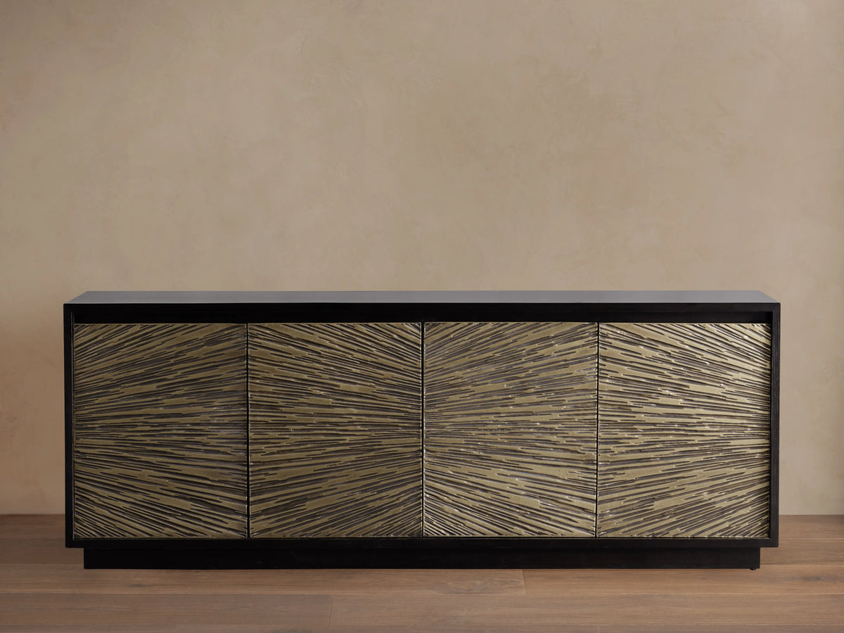 Helios Sideboard with ebony-stained frame and four doors featuring brass sheeting in a sunburst pattern, on wooden floor.