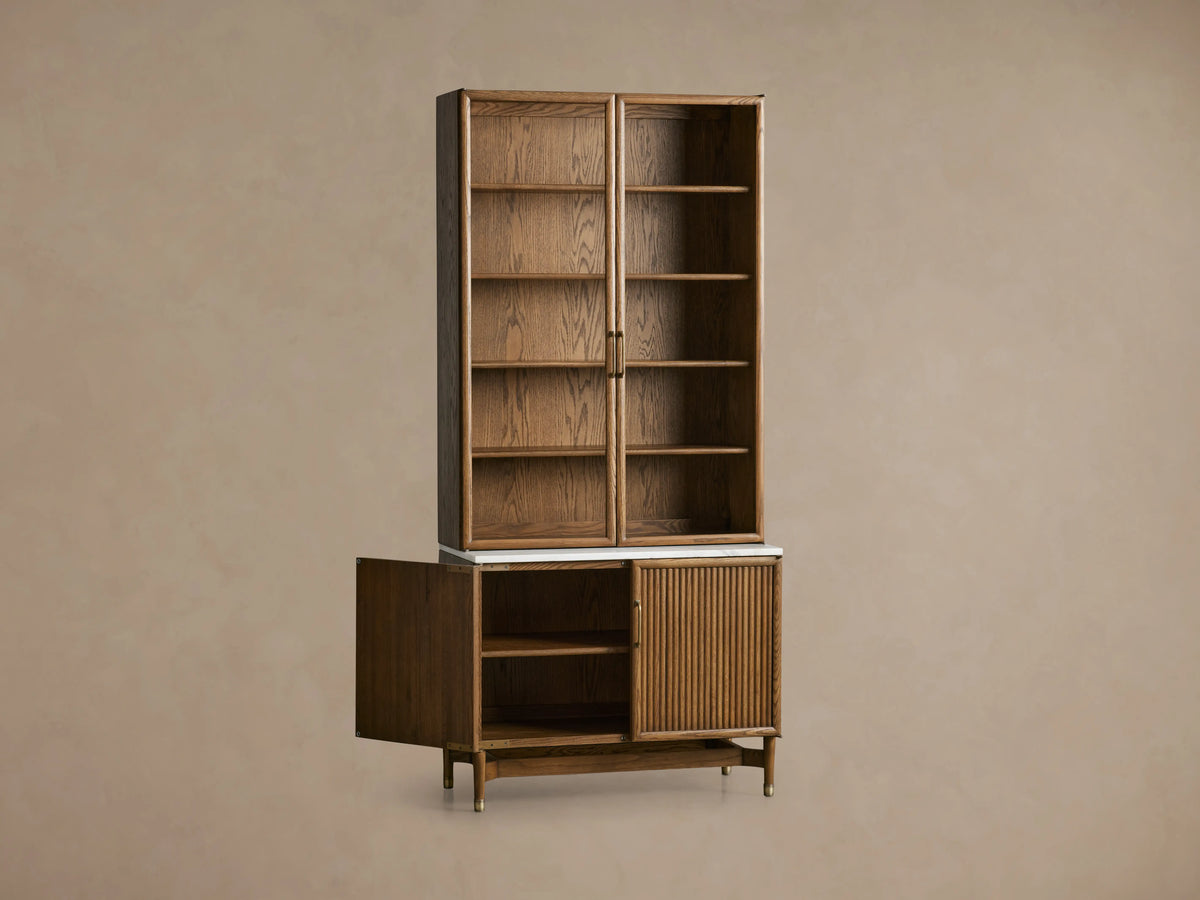Henderson Cabinet with upper glass doors and shelves, lower wood panel door, honey wood finish, and Carrara marble top.
