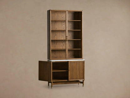 Henderson Cabinet with upper glass doors and shelves, lower wood panel door, honey wood finish, and Carrara marble top.