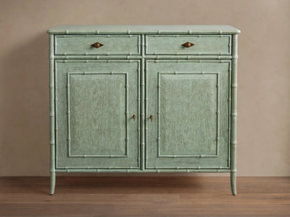 Patinated light green Iris Hall Chest with bamboo framing, two drawers with bronze diamond pulls, and two paneled doors.