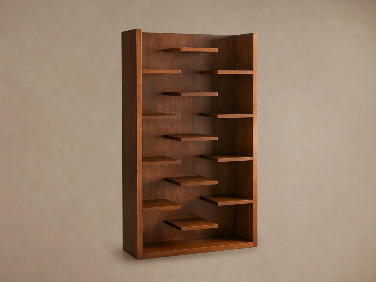 James Bookcase made of walnut veneers in Classic Walnut finish, featuring 13 staggered floating shelves against a smooth wall.