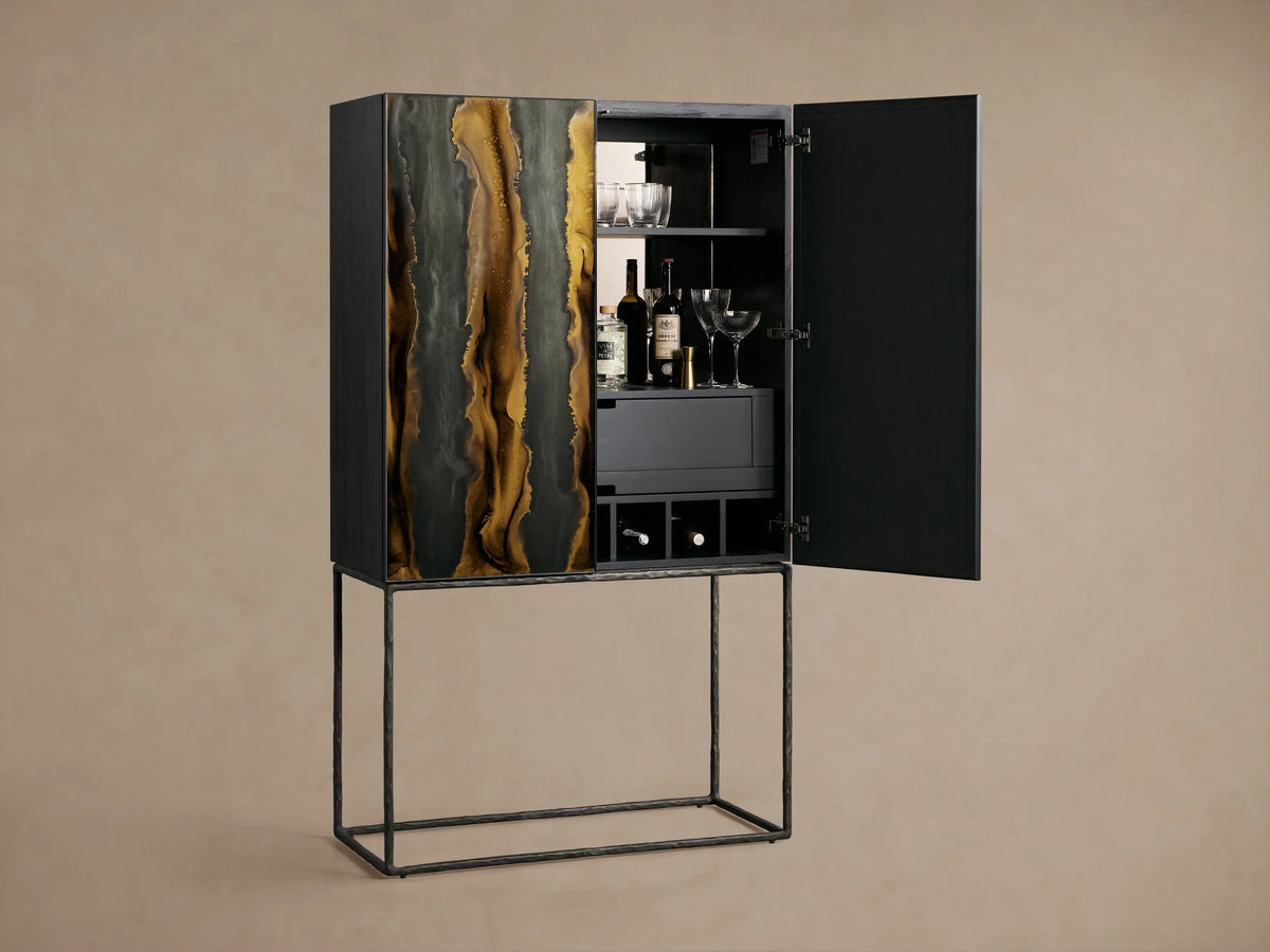Mareta Bar Cabinet with black and gold marbled vertical wave patterns on doors, standing on a sleek metal base against a neutral wall.