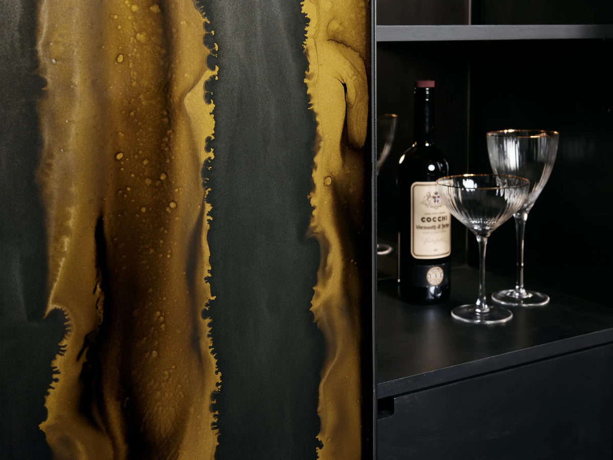 Mareta Bar Cabinet with an open door showcasing shelves with glasses and bottles. Dark exterior with abstract gold and black design.
