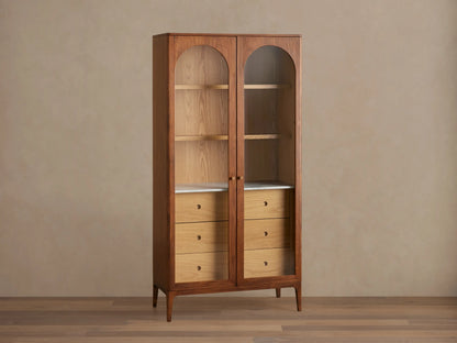 Linley Glass Cabinet with walnut finish, featuring brass knob pulls, adjustable shelves, and three drawers on a Carrara stone surface.