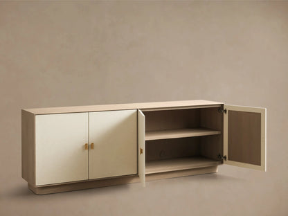 Front view of a long cream credenza with four doors, light wood top and base, and brass rectangular pull handles.