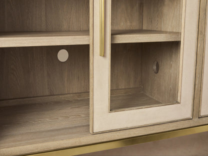 Close-up of Malone Sideboard's upper right corner. Light wood top, cream shagreen panels, metallic gold handles, and glass doors.
