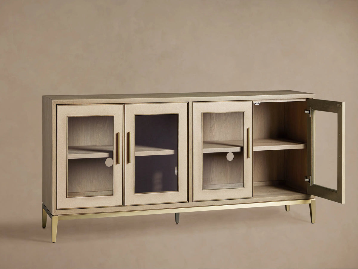 Close-up of Malone Sideboard with glass door, light wood shelves, brass handle & trim, and textured cream shagreen frame.