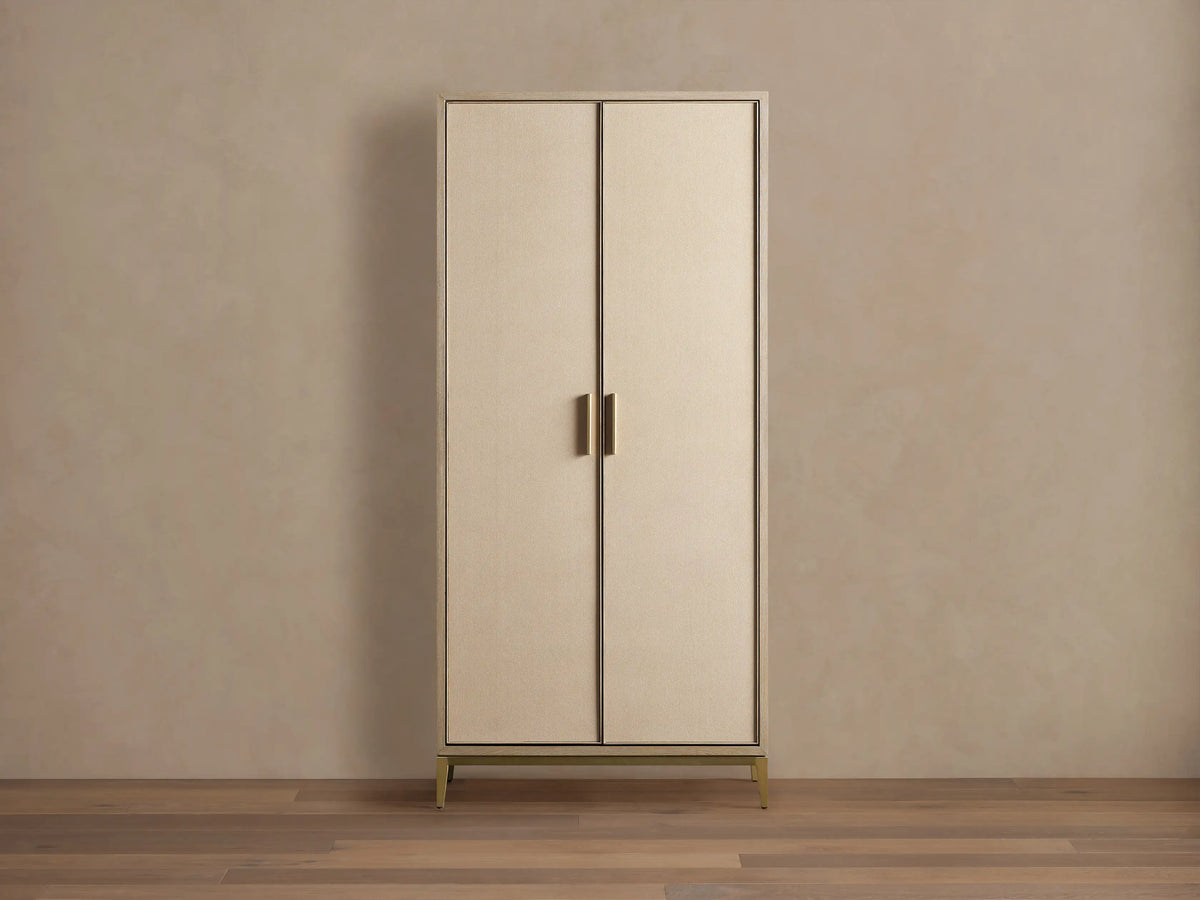Malone Cabinet: Upright, two light beige doors with textured shagreen, dark trim, brass handles & base on a wooden floor.