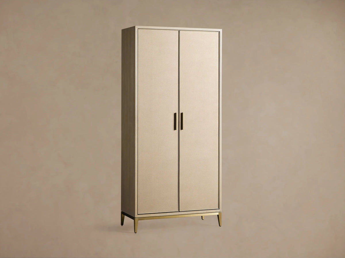 Malone Cabinet: Upright, two light beige doors with textured shagreen, dark trim, brass handles & base on a wooden floor.